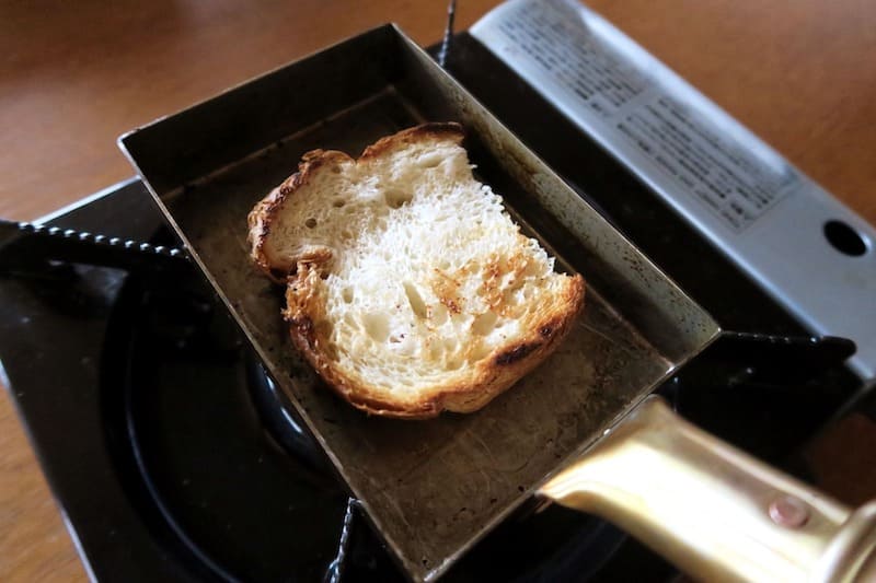食パンを銅の玉子焼き器でトーストしている様子