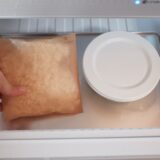 クッキングシートで包んだご飯とガラスのタッパーに入れたご飯を冷凍している様子