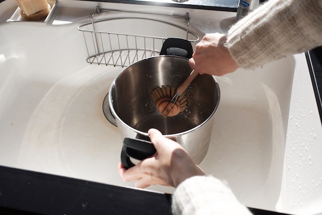 キッチンブラシで深い鍋を洗っている様子